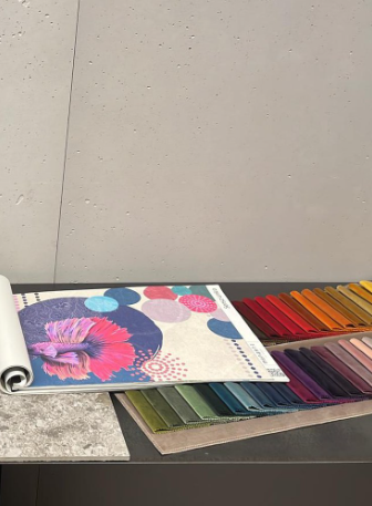 Tavolo campioni in showroom con carta da parati, marmo e campionario di tessuti colorati